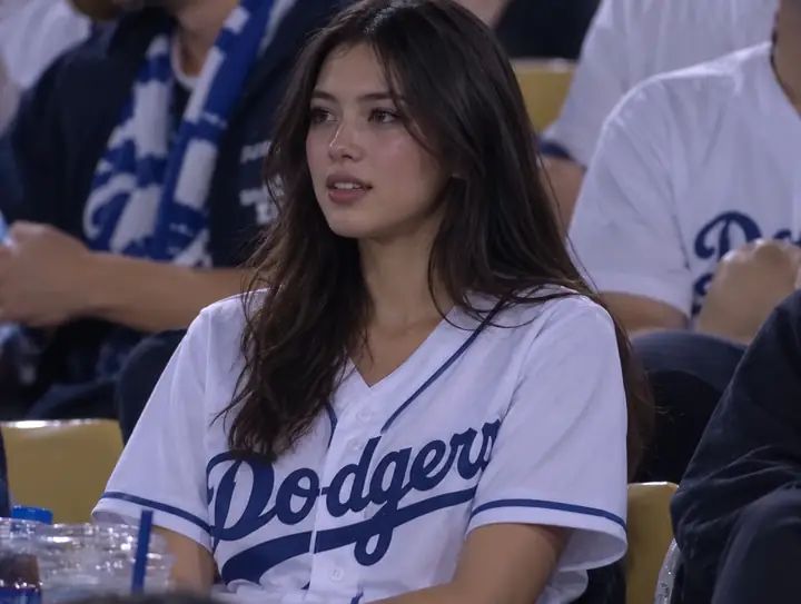 Ein Zuschauer im Baseballtrikot sitzt inmitten einer Menschenmenge.